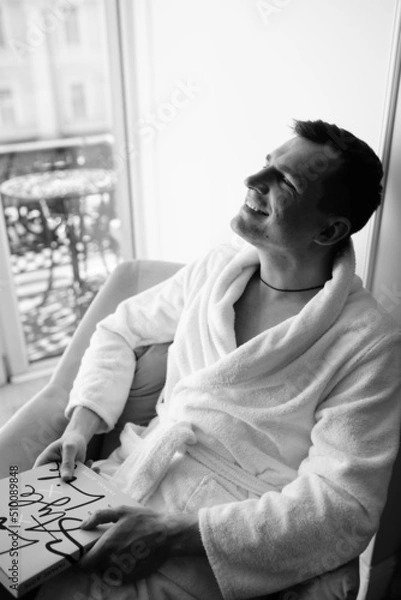 Fototapeta in the photo, a smug man in a bathrobe in hotels lying down enjoying the view from the window