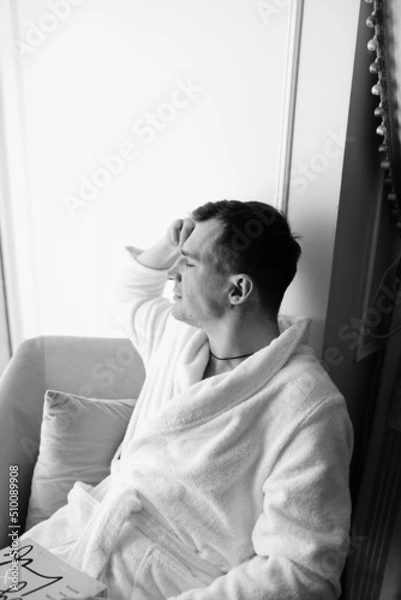 Fototapeta in the photo, a smug man in a bathrobe in hotels lying down enjoying the view from the window