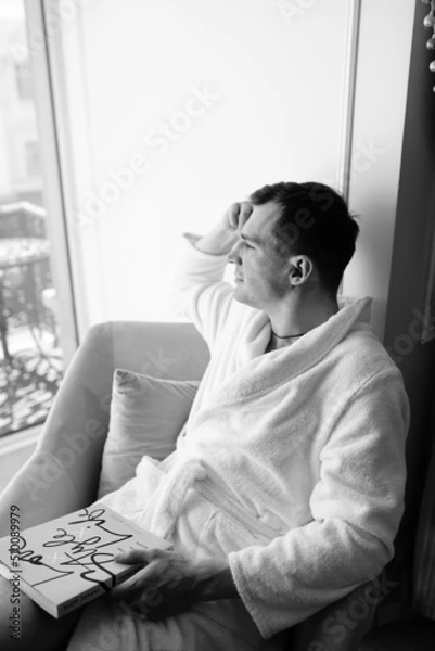 Fototapeta in the photo, a smug man in a bathrobe in hotels lying down enjoying the view from the window