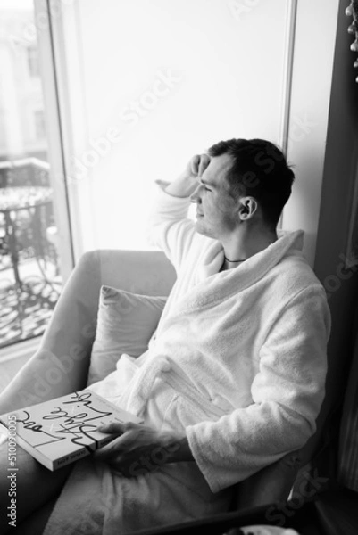 Fototapeta in the photo, a smug man in a bathrobe in hotels lying down enjoying the view from the window