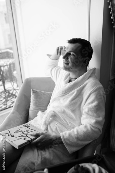 Fototapeta in the photo, a smug man in a bathrobe in hotels lying down enjoying the view from the window