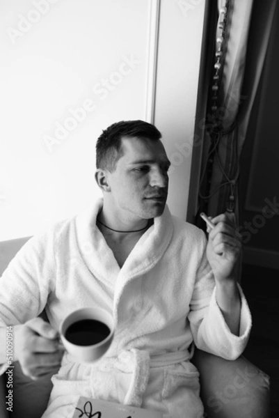 Fototapeta in the photo, a smug man in a bathrobe in hotels lying down enjoying the view from the window