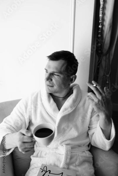Fototapeta in the photo, a smug man in a bathrobe in hotels lying down enjoying the view from the window