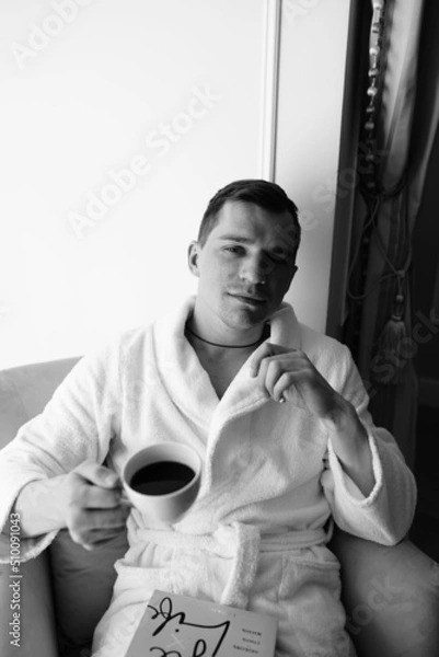 Fototapeta in the photo, a smug man in a bathrobe in hotels lying down enjoying the view from the window