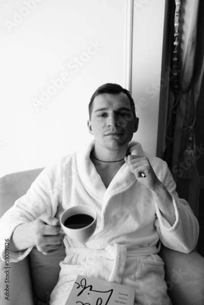 Fototapeta in the photo, a smug man in a bathrobe in hotels lying down enjoying the view from the window