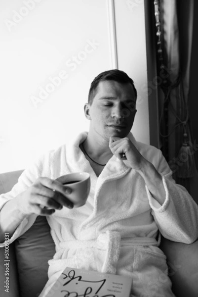 Fototapeta in the photo, a smug man in a bathrobe in hotels lying down enjoying the view from the window