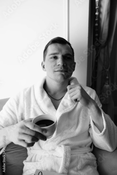 Fototapeta in the photo, a smug man in a bathrobe in hotels lying down enjoying the view from the window
