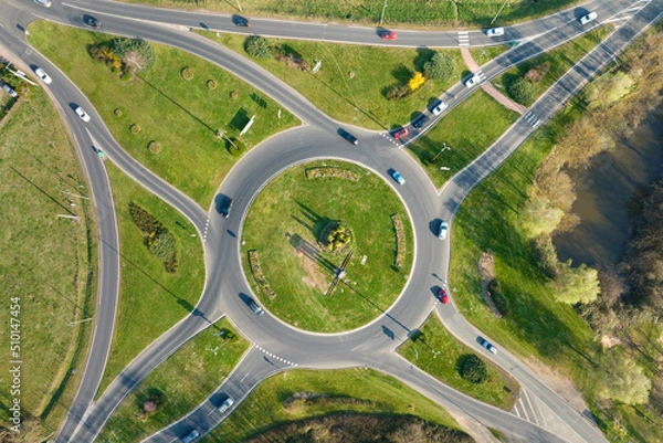 Fototapeta Aerial view of road roundabout intersection with moving heavy traffic. Urban circular transportation crossroads