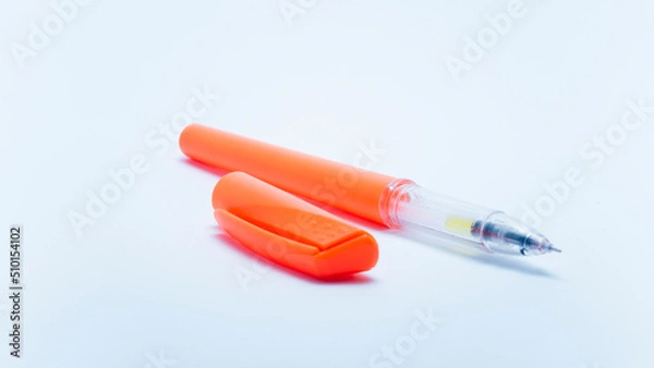 Fototapeta Photo of a bright orange ballpoint pen on a white background. Suitable for design elements of education, office stationery, and student study supplies.