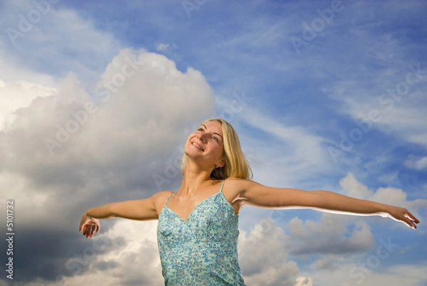 Fototapeta Beautiful blond girl with arms wide open over blue cloudy sky