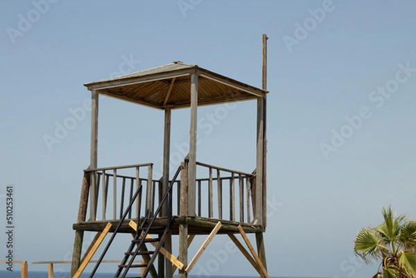 Fototapeta Lifeguard tower at the beach in the background blue sea and sky.