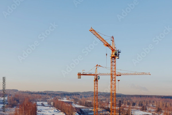 Fototapeta building cranes at the construction site on blue sky background