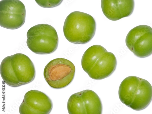 Fototapeta Green cherry plum on a white background. Fruit for making tkemali sauce. . Useful fruits. Sweet and sour fruit. Juicy cut green plum