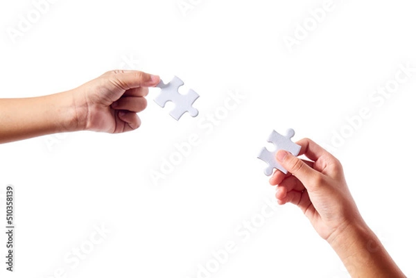 Fototapeta Close up hand two people holding jigsaws connecting puzzle elements on white isolated background