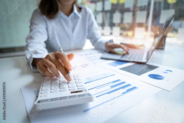 Fototapeta Close up Businessman using calculator and laptop for calculating finance, tax, accounting, statistics and analytic research concept
