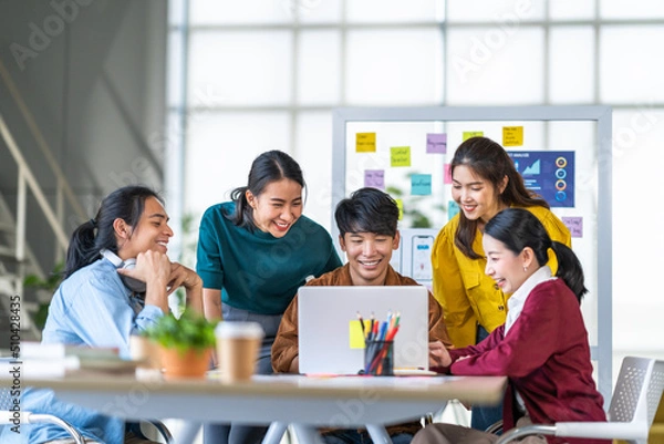 Fototapeta Young happy Asian business man, woman work together in start up office. Creative team brainstorm meeting, internet technology, businesspeople colleague partnership, or office coworker teamwork concept