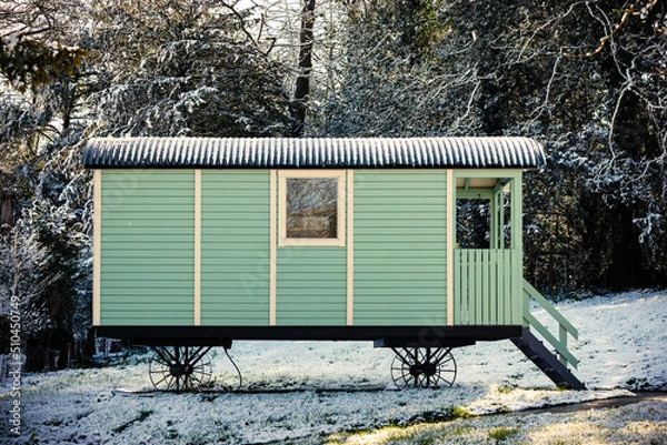 Fototapeta Beautiful vintage mint green shepherd's hut or wagon on cast iron wheels in a snow scene