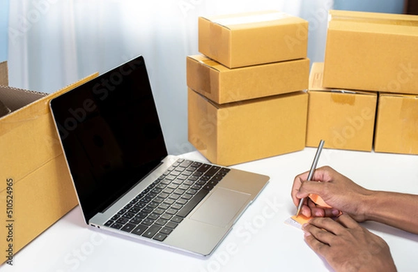 Fototapeta Shipment Online Sales .Man worker delivery service and working packing box, business owner working checking order to confirm before sending customer in post. Online selling, e-commerce Start up.
