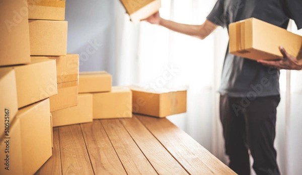 Fototapeta Young entrepreneur business owner work at home, small business startup receive order client and take note working with report and pack the product on purchase delivery online to sending destination.