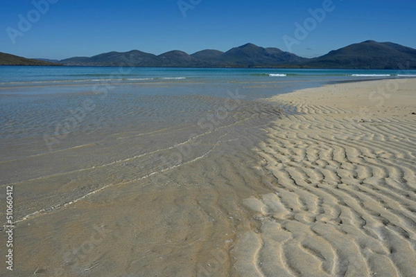 Fototapeta Luskentyre beach, Isle of Harris. Blue sky, mountains in background, sea and wavy lines of sand in foreground. No people. Tranquil, summer scene.