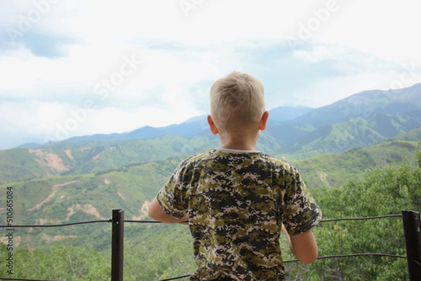 Fototapeta Young thoughtful teenage boy is standing on a balcony and thinking about life.