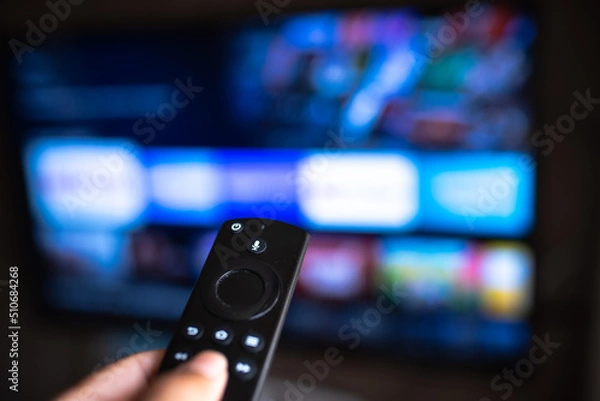 Fototapeta Rio de Janeiro / Brazil- February 3, 2021: amazon fire tv stick remote in hand with selective focus tv background. During the COVID-19 lockout.
