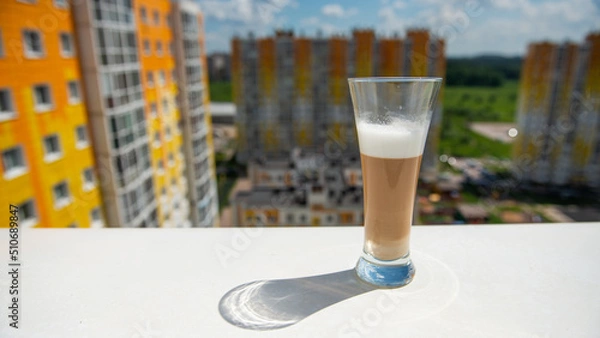 Fototapeta multilayer coffee on a white windowsill overlooking the city