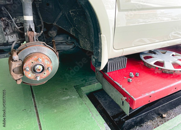 Obraz 自動車のタイヤ交換をガレージで行っている画像