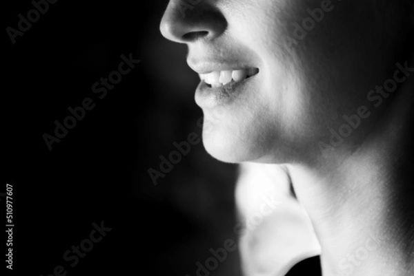 Fototapeta BW photo of an attractive woman. A large portrait on a dark background. Macro photo, bottom part of the face. Front view.