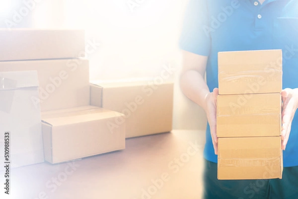 Fototapeta Small business owner packing in the cardbox at workplace. Cropped shot of man preparing a parcel for delivery at online selling business office. Ecommerce drop shipping shipment service concept.