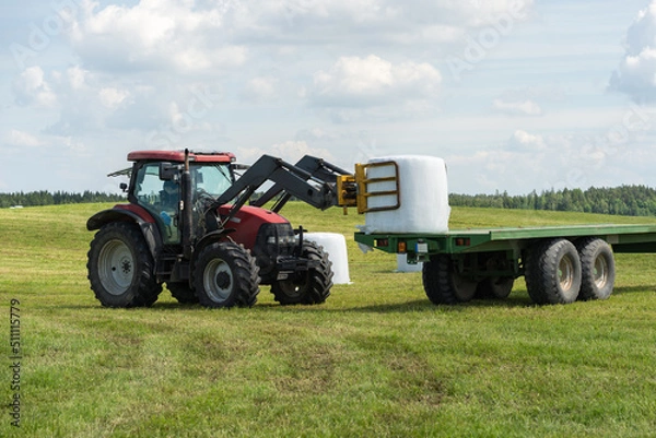 Obraz Farmer load hay bales to trailer.