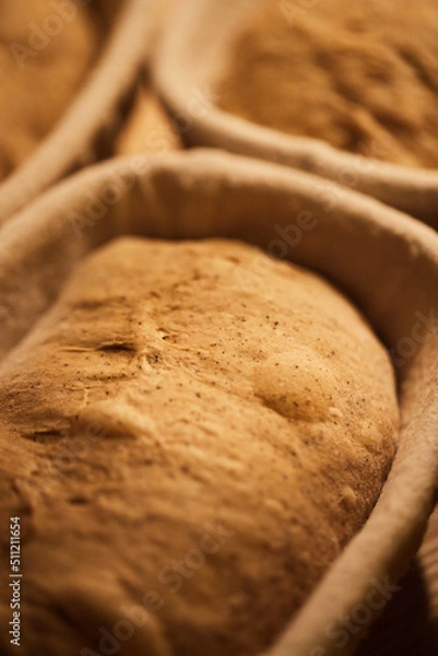 Fototapeta Process of making wheat bread at home. Proofing of the dough in rattan baskets. The concept of healthy homemade food. Vertical photo.