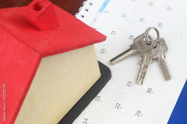 Obraz Wooden house model on calendar page with keys. Real estate rent and investments concept.