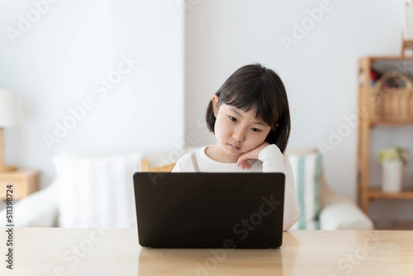 Fototapeta パソコンを使いながら困った顔をする女の子