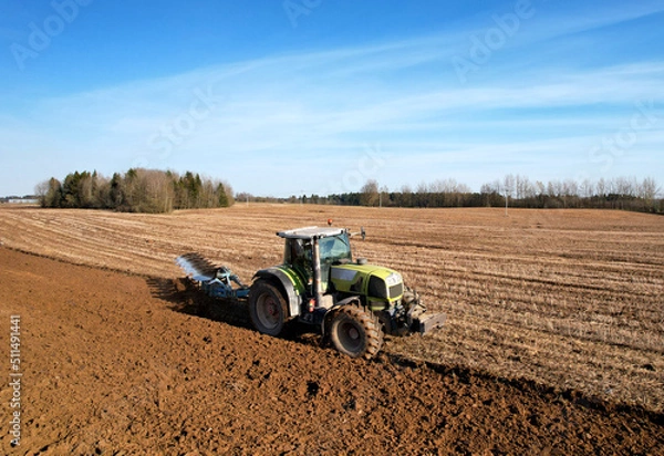 Fototapeta Tractor plowing field. Tractor plow soil cultivating. Cultivated land and soil tillage. Agricultural tractor on farm field cultivation. Tractor disk harrow plowing farm field. Agronomy and agrarian..