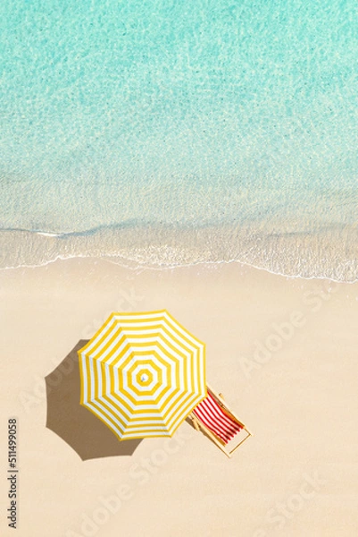 Fototapeta Top view of sunbed, lounge, yellow umbrella, SUP board for surfing on the shore on tropical Seychelles sand beach. Blue, turquoise transparent water surface of ocean, sea. Aerial, drone view. vertical
