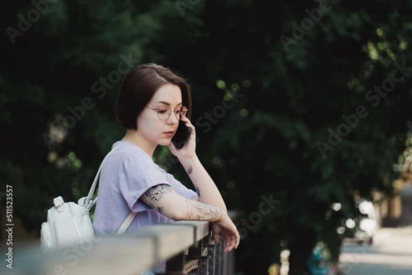 Fototapeta Young Girl Talks on Phone on Street in City Center