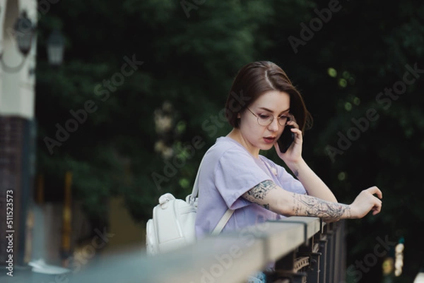 Fototapeta Young Girl Talks on Phone on Street in City Center