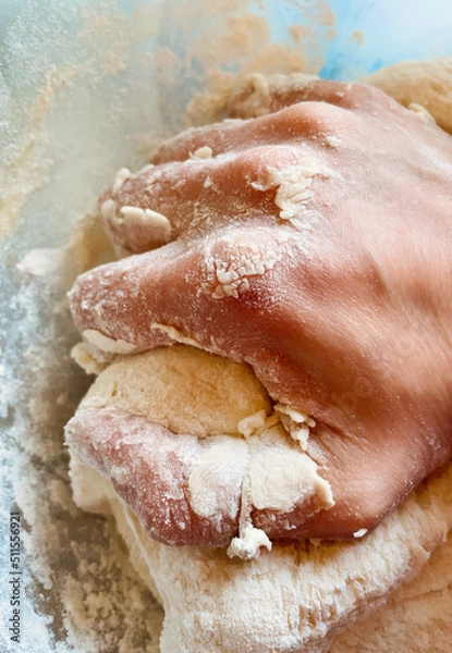 Fototapeta Woman hand kneading dough in bowl sprinkled with flour