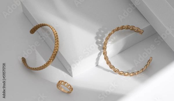 Fototapeta Shiny Modern gold braid shape and chain shape bracelets and ring on white geometric background