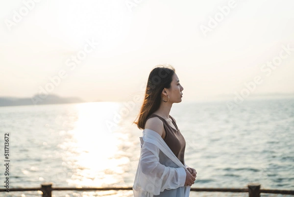 Fototapeta 夕暮れの海にいる女性