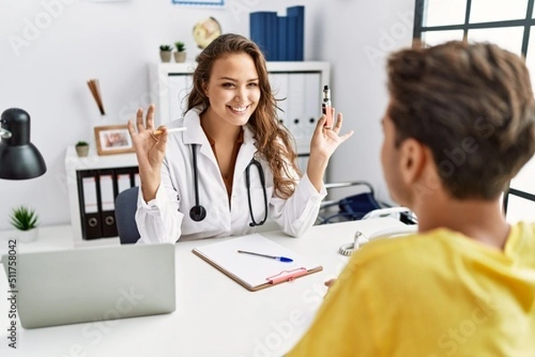 Fototapeta Young doctor woman showing electronic cigarette and normal cigarrete to patient smiling with a happy and cool smile on face. showing teeth.