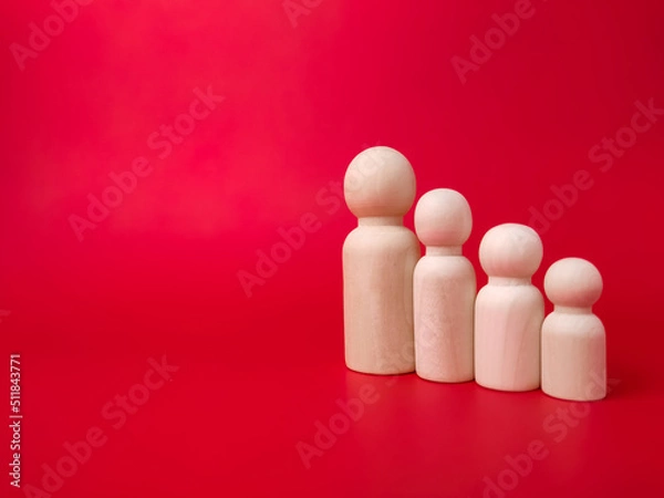 Fototapeta Wooden figures lined up according to their respective heights on red background with copy space.