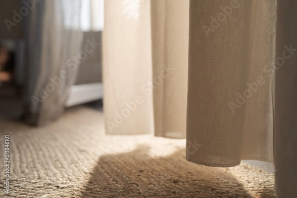 Fototapeta Closeup photo of jute rug on a floor with curtains on background with warm sun light