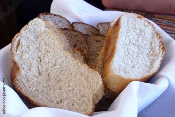 Fototapeta white bread cut into chunks in a plate with a white napkin on the table