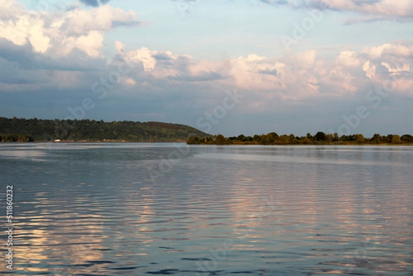 Fototapeta the island with a chapel on the river sunset the sun is reflected in the water