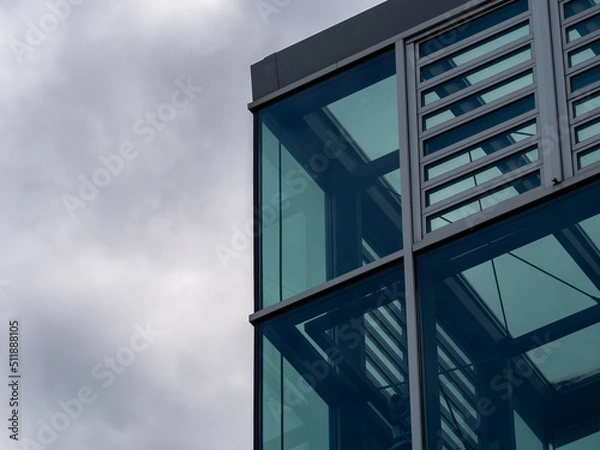 Obraz Modern building architecture with big glass windows. Exterior of a contemporary building with steel elements on the facade. New empty office house in the city with a minimalistic business style.