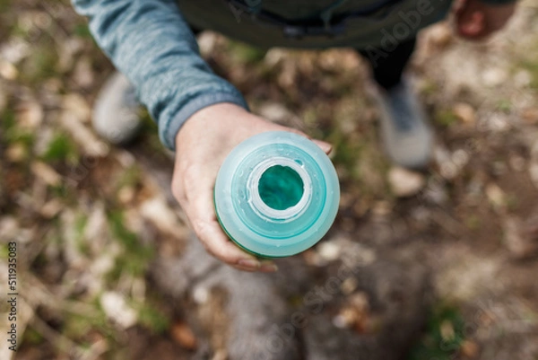 Obraz Woman drinking water from bottle. Resting during hiking in forest. Top view. Fitness and sport activity