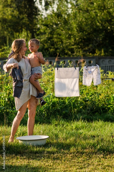 Obraz woman with children in garden hanging laundry outside, lifestyle people concept