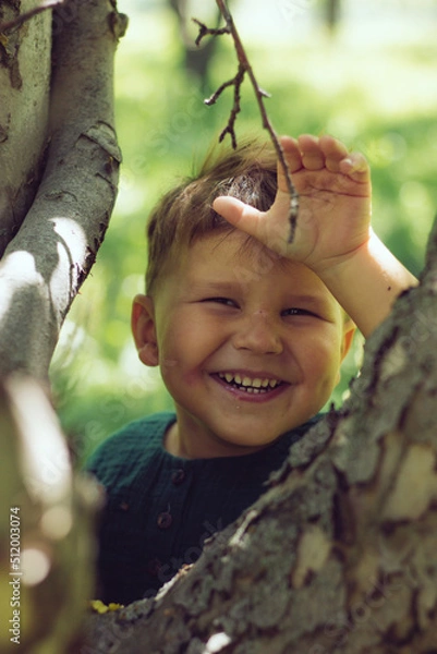 Fototapeta Portrait of a child boy in green clothes near a tree
